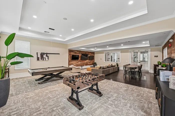 Luxurious recreation room featuring a modern pool table, foosball, and cozy seating area, perfect for entertainment and relaxation.