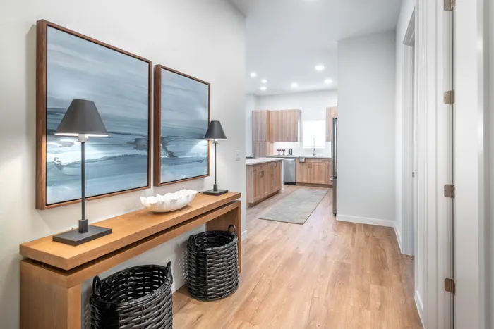 Elegant hallway leading to a modern kitchen with wooden cabinets, stylish artwork, and sophisticated lighting.