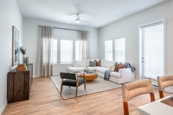Bright and inviting living room featuring a cozy white sectional, elegant wooden furniture, and abundant natural light creating a serene atmosphere.