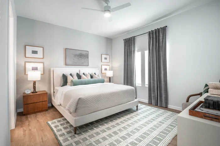 Inviting bedroom with a cozy bed, elegant decor, and natural light filtering through large windows.