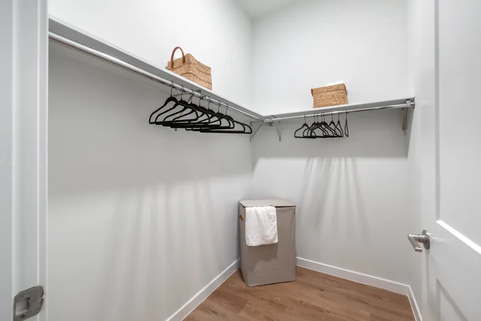 Spacious walk-in closet with sleek wooden floors, ample hanging space, and stylish storage solutions.