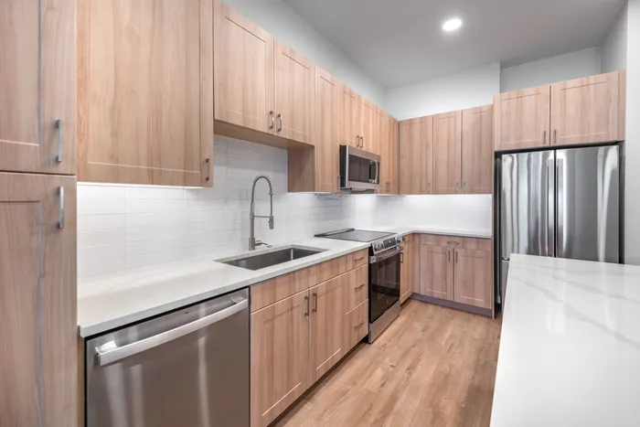 Modern kitchen with sleek stainless steel appliances and elegant wood cabinetry, featuring a spacious counter and contemporary design.
