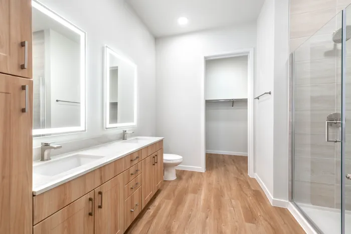 Luxurious bathroom with modern dual sinks, elegant wooden cabinetry, and a sleek glass shower for a spa-like experience.