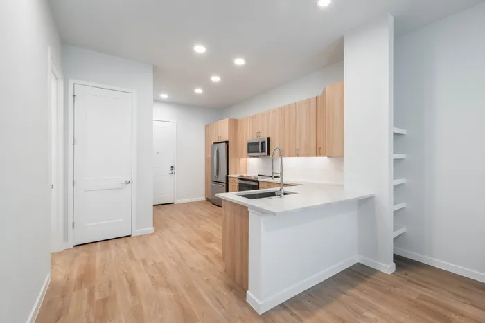 Chic modern kitchen with light wood cabinetry, sleek appliances, and elegant countertops in a bright open space.