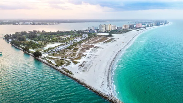 Breathtaking aerial view of a stunning coastal peninsula with lush greenery, pristine white sandy beaches, and vibrant turquoise waters, perfect for waterfront living.