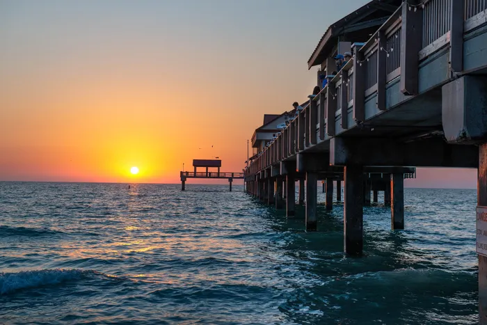 Breathtaking sunset over the ocean with a pier extending into the water, creating a serene and picturesque coastal view.