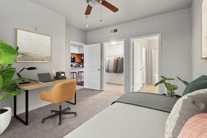 Bright and inviting bedroom with a cozy workspace, walk-in closet, and modern decor seamlessly linked to an elegant kitchen.