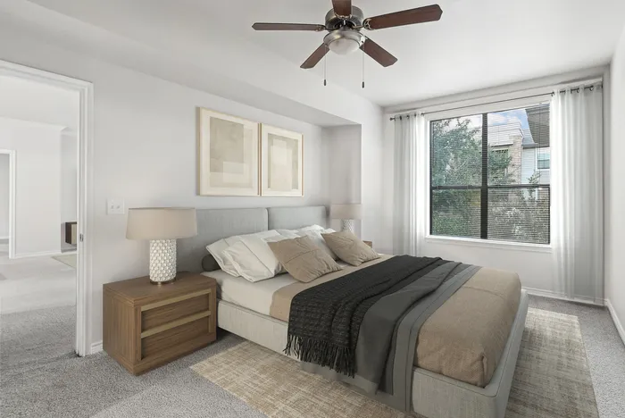 Bright and inviting bedroom with elegant decor, featuring a plush bed, modern ceiling fan, and large window letting in natural light.