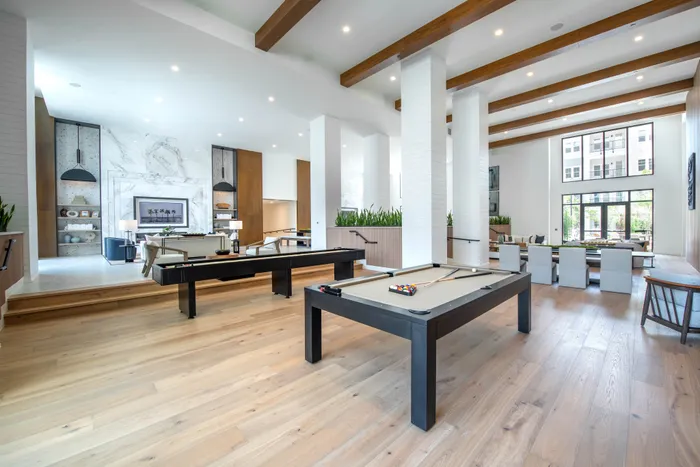 Luxurious open-concept lounge area featuring sleek pool tables, elegant seating, and modern decor with floor-to-ceiling windows.