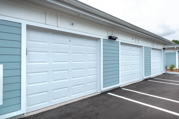 Modern apartment complex with stylish blue and white garages, ample parking space, and well-maintained surroundings.