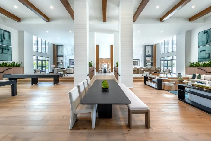 Luxurious open-concept living space with modern decor, featuring high ceilings, elegant wooden beams, and a sophisticated dining area.