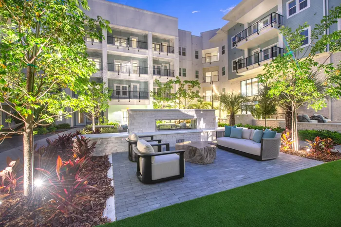 Luxurious apartment courtyard featuring cozy seating, lush greenery, and elegant architecture.