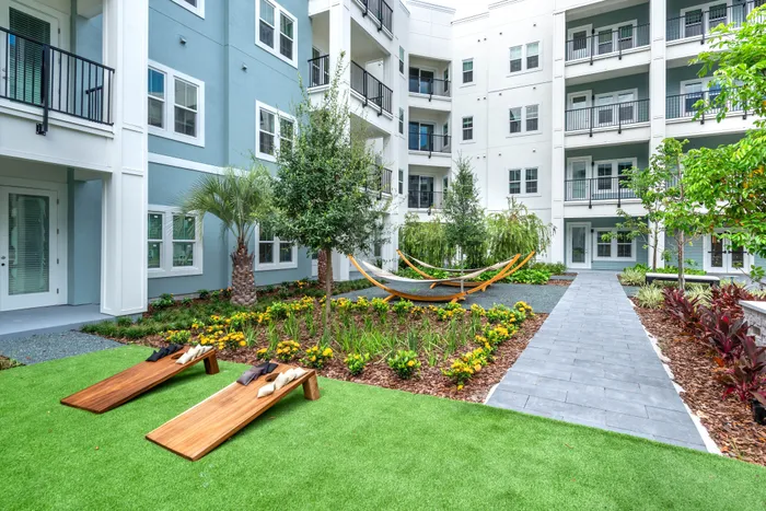 Modern apartment courtyard showcasing lush gardens, inviting hammocks, and natural wood seating.