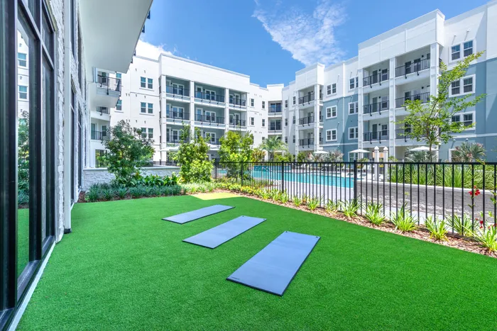 Luxurious apartment complex with beautifully landscaped green space and inviting pool, perfect for relaxation and outdoor activities.