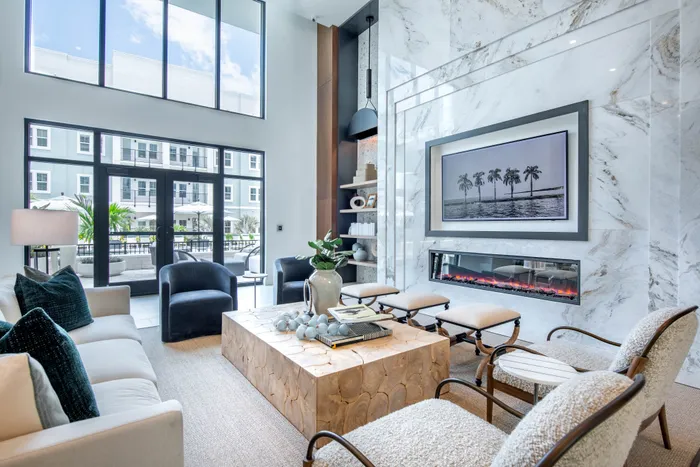 Luxurious living room with high ceilings, large windows, and a contemporary marble fireplace in a modern apartment.