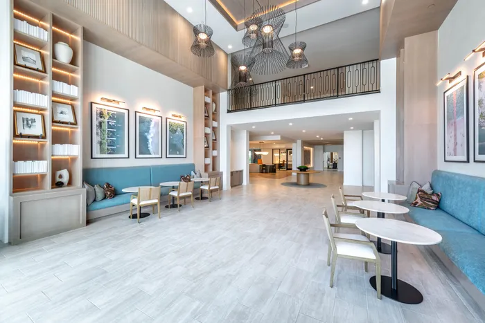 Elegant modern lobby with stylish seating, artistic wall decor, and inviting high ceilings illuminated by chic pendant lights.