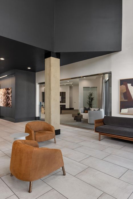 Modern lobby area with chic leather chairs, sleek grey sofa, and elegant art piece on the wall.
