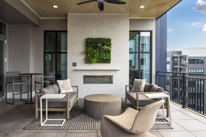 Modern outdoor living space with stylish seating, elegant fireplace, and lush green wall accent.