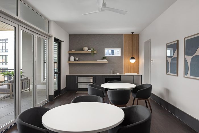 Contemporary dining area with sleek tables and stylish chairs, featuring a modern kitchenette and open balcony view.