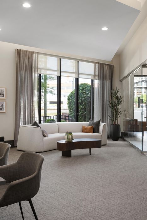 Modern living room with a cozy white sofa, stylish coffee table, and large windows offering abundant natural light.