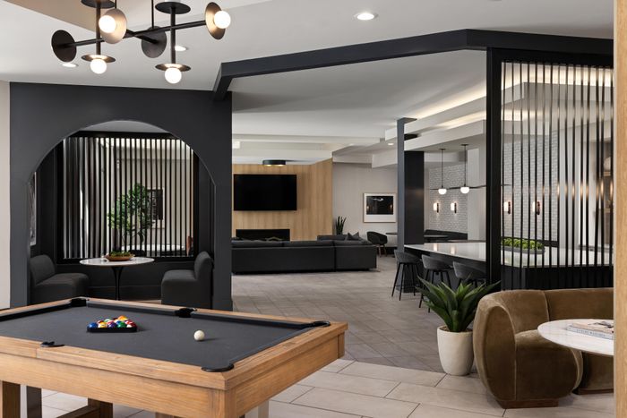 Modern lounge area with a stylish billiards table, plush seating, and an inviting open-concept design featuring contemporary lighting and sleek decor.