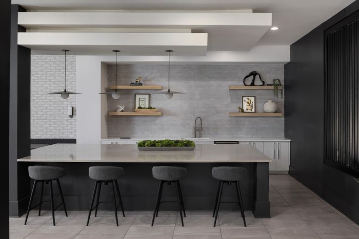 Modern kitchen with sleek countertops, stylish bar stools, and elegant open shelving complimented by contemporary decor.