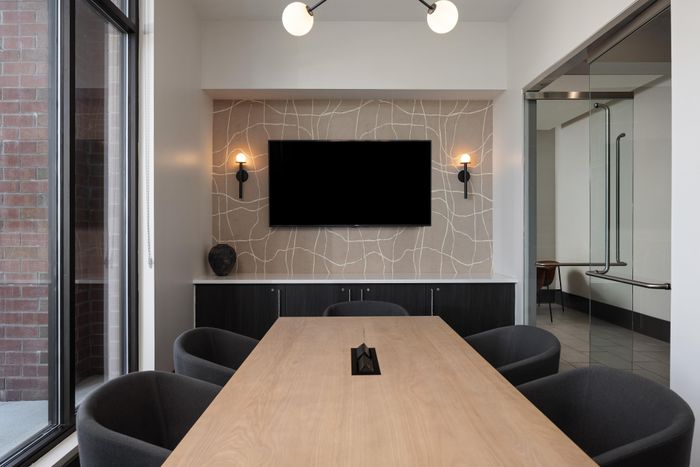Elegant conference room with a sleek wooden table, modern lighting, and a spacious glass entryway, perfect for dynamic meetings.