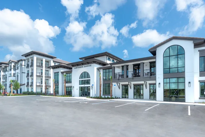 Elegant apartment complex with modern architecture and large windows under a bright blue sky, offering luxurious living at Lantower Sunrise.