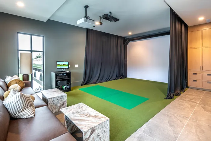 Luxurious indoor golf simulator room with sleek leather seating, modern decor, and state-of-the-art technology for an immersive experience.