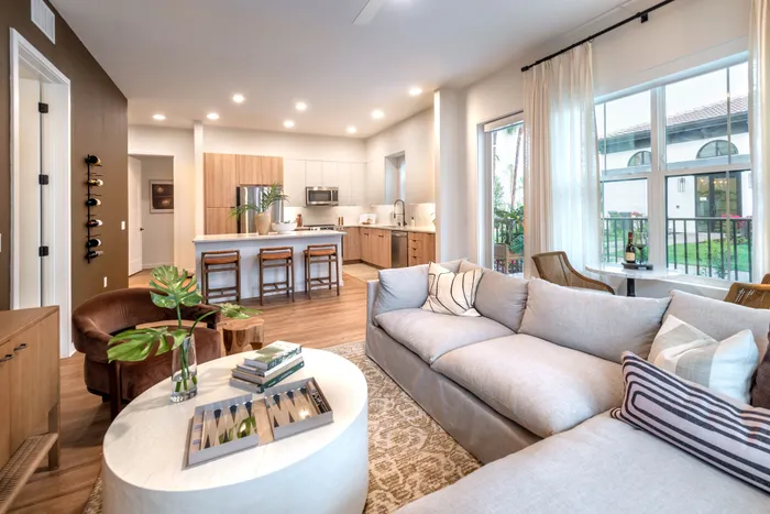 Inviting open-concept living room with plush sofa, elegant kitchen island with seating, and large windows providing abundant natural light.