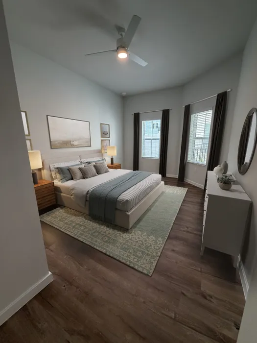 Elegant bedroom with modern decor, featuring a cozy bed, stylish wooden flooring, and abundant natural light through large windows.