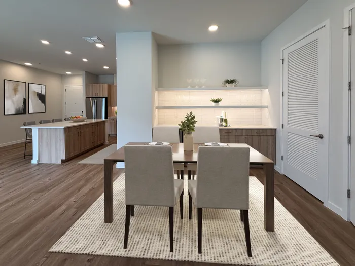 Modern open-concept dining and kitchen area with sleek wooden flooring, elegant cabinetry, and contemporary decor.