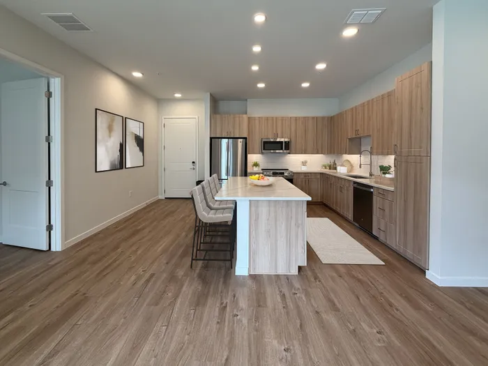 Modern open-plan kitchen with wood flooring, sleek cabinetry, and a spacious island with stylish bar seating.