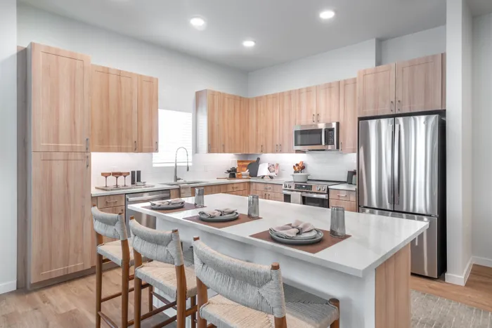 Sleek and modern kitchen with stylish wooden cabinetry, stainless steel appliances, and a spacious island with seating for four.