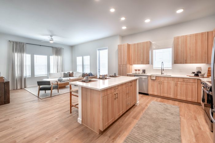 Beautiful open-concept kitchen and living area with modern light wood cabinetry, spacious island, and cozy seating arrangement.