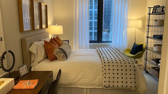 A Carpeted Bedroom with a Queen Sized Bed and Large Window.