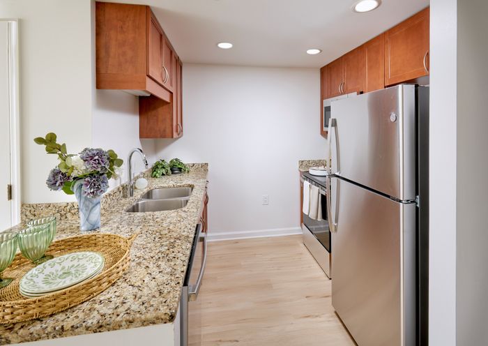 Renovated Schubert Studio kitchen with granite countertops, custom wood cabinets, stainless steel appliances, and new wood-style vinyl flooring | Meridian at Grosvenor Station | Luxury North Bethesda MD Apartments | Luxury Rockville MD Apartments