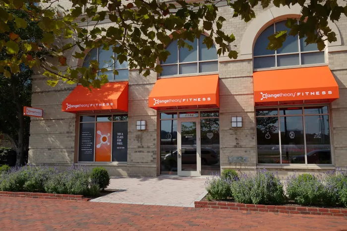 Street view of the Orangetheory Fitness gym entrance on Eisenhower Avenue, showing the modern retail facade of the Meridian building.