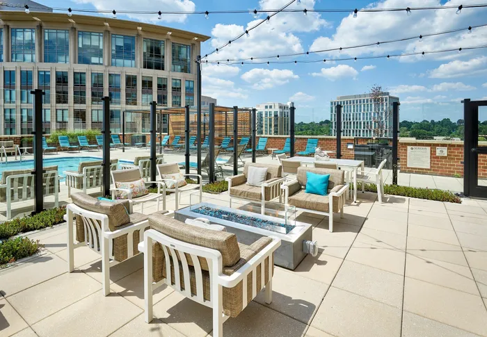 Outdoor resident lounge at Meridian at Eisenhower Station featuring a fire pit, string lights, and multiple modern seating areas. | Luxury Alexandria VA Apartments
