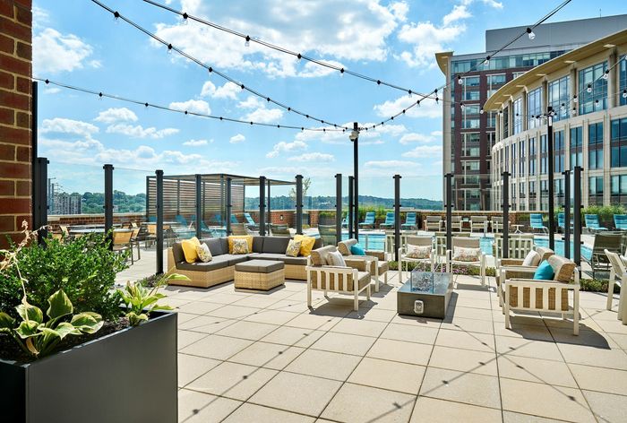 Outdoor resident lounge at Meridian at Eisenhower Station featuring a fire pit, string lights, and multiple modern seating areas. | Luxury Alexandria VA Apartments