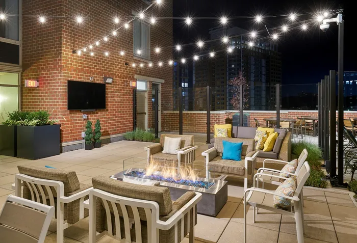 Outdoor resident lounge at Meridian at Eisenhower Station featuring a fire pit, string lights, and multiple modern seating areas. | Luxury Alexandria VA Apartments