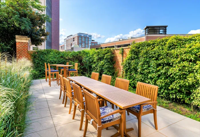 Apartment courtyard with outdoor grills, dining tables, and a view of the Washington Masonic Memorial. | Meridian at Eisenhower Station | Luxury Alexandria VA Apartments