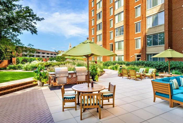 Apartment courtyard with outdoor grills, dining tables, and a view of the Washington Masonic Memorial. | Meridian at Eisenhower Station | Luxury Alexandria VA Apartments