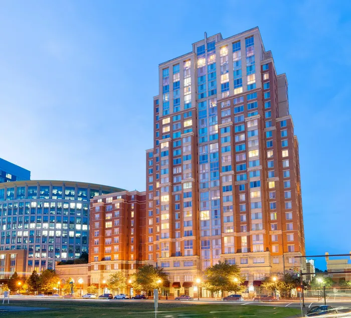 Meridian at Eisenhower Station building at night with lit windows and Alexandria city skyline.