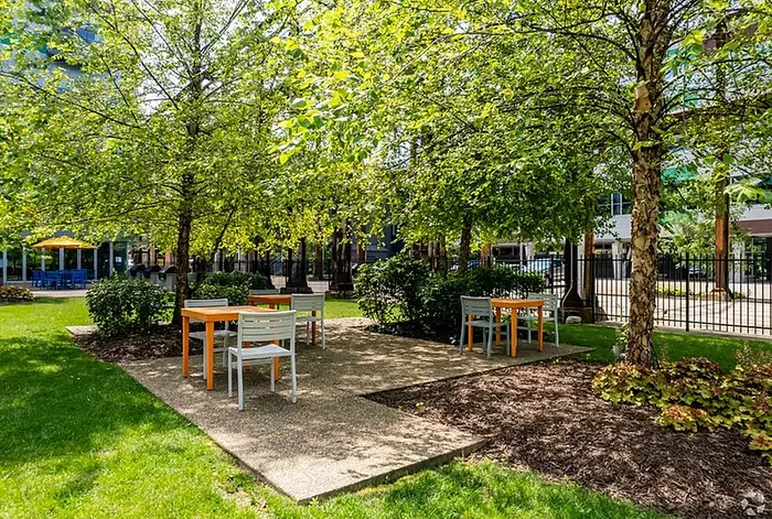 Charming outdoor communal area featuring lush greenery, shaded seating, and a welcoming atmosphere perfect for relaxation and gatherings.