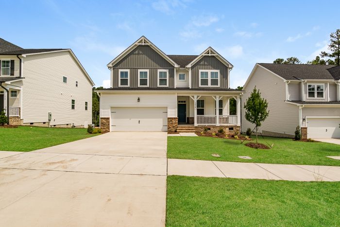 Charming two-story house with elegant front porch and spacious garage, set in a vibrant suburban neighborhood.