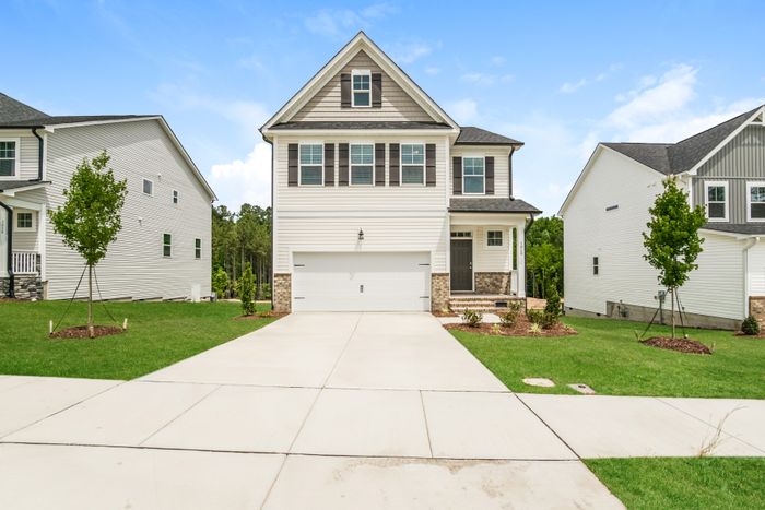 Charming two-story suburban house with a beautiful front yard, wide driveway, and modern architectural details.