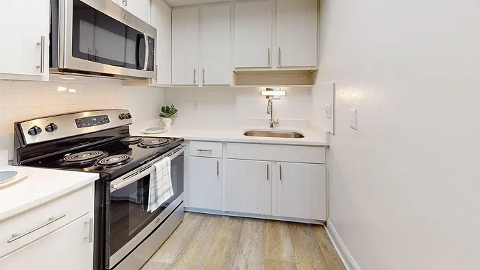 Modern kitchen with stylish stainless steel appliances, sleek white cabinetry, and elegant wood flooring, ideal for culinary enthusiasts.