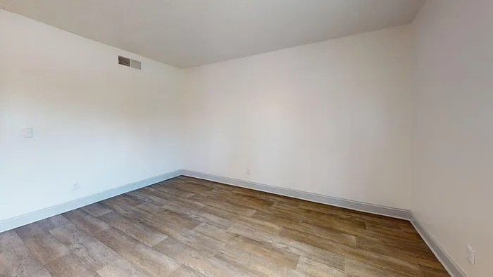Inviting modern room with elegant hardwood flooring, featuring neutral walls and ample natural light.