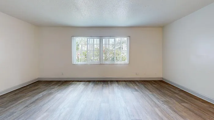 Bright and spacious living room with large windows and elegant wood-look flooring, perfect for creating a warm and inviting atmosphere.